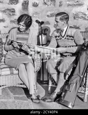 1920ER JAHRE JUNGE AKTIVE GUT-ZU-TUN-PAAR MANN FRAU MANN FRAU SITZEN AUF DER VERANDA BLICK AUF GOLFSCHLÄGER STILVOLLE MODISCHE KLEIDUNG - G3281 HAR001 HARS VORSTADTVERANDA ALTE ZEIT GESCHÄFTIGE NOSTALGIE ALT MODE 1 STIL BALANCE WOHLHABENDEN WETTBEWERB INFORMATIONEN ATHLET MODISCH REICH FREUDE LIFESTYLE ZUFRIEDENHEIT FRAUEN VERHEIRATET EHEGATTEN EHEMÄNNER GESUNDHEIT ATHLETIK LUXUS WOLLE KOPIE RAUM IN VOLLER LÄNGE DAMEN PERSONEN MÄNNER SPORTLICH S & W PARTNER CLUBS KURS GLÜCK WELLNESS FREIZEIT STILE WAHL AUFREGUNG AUSSEN FRISUR WISSEN REICHTUM STOLZ AUF GEHOBENE KONZEPTIONELLE WOHLHABENDE ATHLETEN INSPEKTION STYLISCH Stockfoto