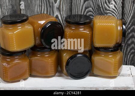 Obstkonfitüre in Gläsern. Steht auf einer weiß bemalten Holzkiste. Vor dem Hintergrund von schwarzen Kieferntafeln. Stockfoto