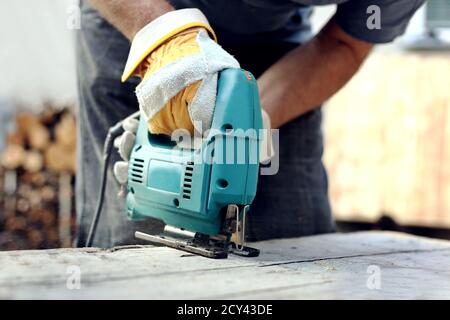 Zimmermann mit Laubsäge zum Schneiden von Holzbrettern. Bau Details der männlichen Arbeiter oder handliche Mann mit Power Tools.Work Prozess in der Zimmerei Stockfoto