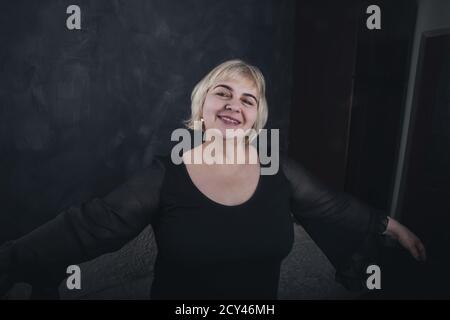 Ältere Frau in schwarzer Kleidung auf einem soliden Hintergrund Ein dunkelgrauer Beton Stockfoto