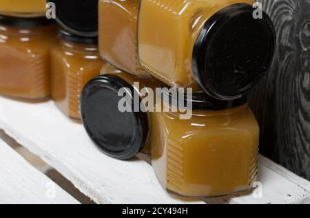 Obstkonfitüre in Gläsern. Steht auf einer weiß bemalten Holzkiste. Vor dem Hintergrund von schwarzen Kieferntafeln. Stockfoto