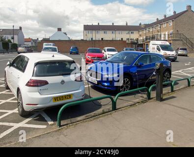 Electric Golf und Jaguar i-Pace werden auf dem öffentlichen Parkplatz in Marske-by-the-Sea aufgeladen. Stockfoto