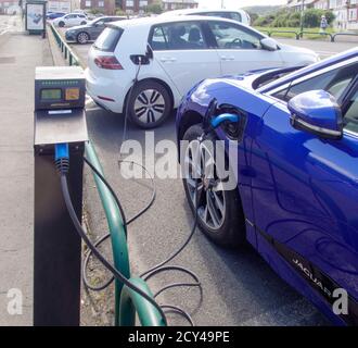 Electric Golf und Jaguar i-Pace werden auf dem öffentlichen Parkplatz in Marske-by-the-Sea aufgeladen. Stockfoto