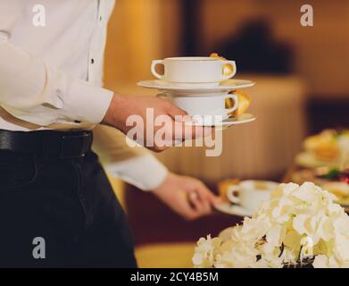 Tasse Kaffee oder Tee in weiblichen Händen auf einem warmen Wrap oder einer Decke. Getöntes Bild. Stockfoto