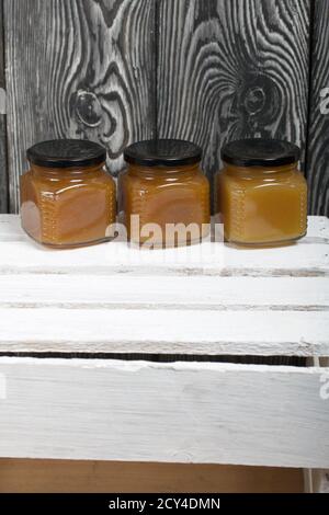 Obstkonfitüre in Gläsern. Steht auf einer weiß bemalten Holzkiste. Vor dem Hintergrund von schwarzen Kieferntafeln. Stockfoto