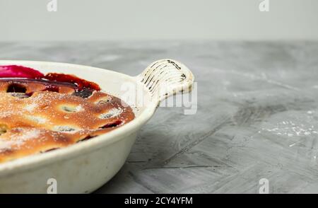 Hausgemachte Clafoutis Kirschkuchen - traditionelle französische Dessert in a Weiße Backform isoliert auf einem grauen Hintergrund mit Kopie Platz Stockfoto