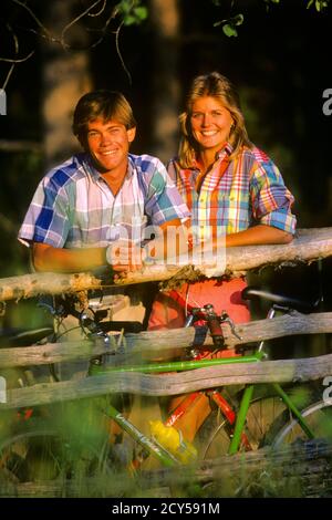 1980 1990ER TEENAGER-PAAR IM FREIEN LÄCHELND TRAGEN PASTELL KARIERTE HEMDEN LEHNEN MIT FAHRRÄDERN AUF HOLZZAUN BLICK AUF DIE KAMERA - KS28177 WAL004 HARS KLEIDUNG NOSTALGISCHE PAAR SCHÖNHEIT FRÜHLING FARBE ALT ZEIT NOSTALGIE LEHNTE ALTE MODE 1 JUVENILE STIL FREUDE LIFESTYLE ZUFRIEDENHEIT FRAUEN LÄNDLICHE GESUNDHEIT KOPIEREN RAUM FREUNDSCHAFT HALBE LÄNGE JUGENDLICHE PERSONEN TUCH MÄNNER TEENAGER JUNGE PLAID SONNIGES VERTRAUEN FAHRRÄDER AUGE KONTAKT RAIL TRÄUME GLÜCK FRÖHLICH ERHOLUNG SHIRTS STOLZ MENSCHEN MÄNNER SMILES VERBINDUNG FRÖHLICH STILVOLLE TEENAGED YUPPIE JUVENILES PASTELL RAIL ZAUN ZWEISAMKEIT YOUNGSTER Stockfoto