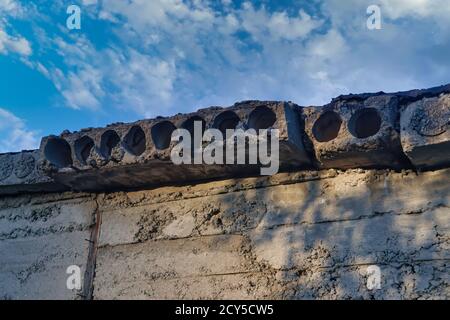 Nahaufnahme der Betonplatten-Oberfläche. Betonplatten mit Löchern vor dem Hintergrund von blauem Himmel und weißen Wolken. Stockfoto