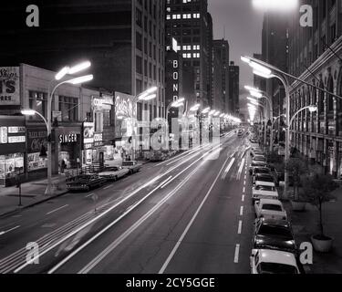 1960ER NACHT AUF STATE STREET IN DER SCHLEIFE VERSCHWOMMEN AUTOMOBIL AMPELN KOMMERZIELLE LADENFRONTEN SCHILDER CHICAGO ILLINOIS USA - R21012 KRU001 HARS AUF DER SCHLEIFE BEWEGUNG BLUR KONZEPTUELLE AUTOMOBILE FRONTEN FAHRZEUGE ILLINOIS NACHT SCHWARZ UND WEISS VERWISCHEN ALTMODISCH Stockfoto