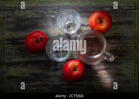Drei rote Äpfel unter Glas Komposition auf verfallenen Holztisch Intentionalisch Teilweise Unterbelichtet Stockfoto
