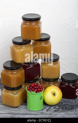 Marmelade in Gläsern. Es gibt einen Apfel und Preiselbeere in der Nähe. Auf schwarzen Kiefernbrettern. Stockfoto