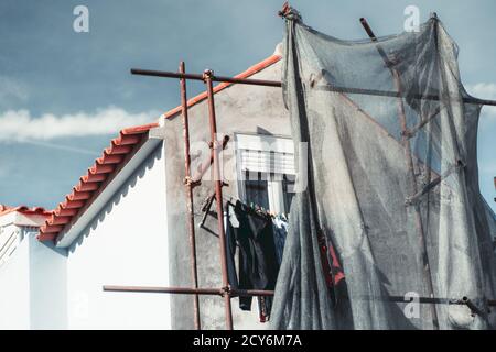 Eine Erhebung eines typischen weißen europäischen Hauses im Bau an einem sonnigen Tag mit Gerüsten und Trocknungskleidung darüber; eine Fassade von unfertigen Por Stockfoto
