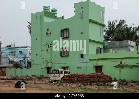 Bhubaneswar, Indien - 4. Februar 2020: Blick auf ein grünes, farbenfrohes Gebäude mit einem Auto und einer Kuh draußen am 4. Februar 2020 in Bhubaneswar, Indien Stockfoto