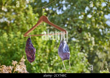 Hausgemachte Gesichtsmasken trocknen in der Sonne auf einem hölzernen Kleiderbügel. Stockfoto