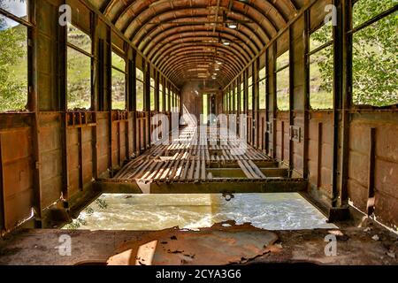 Eine alte Eisenbahn Auto hat als eine Brücke über einen Bach außerhalb Kutasi, Georgien benutzt worden, aber hat jetzt Links zu bröckeln. Stockfoto