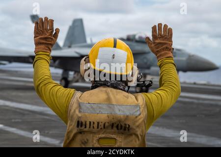 Der Mate (Handling) der 3. Klasse Mohammed Iacovacci aus Detroit signalisiert nach der Landung auf dem Flugdeck des einzigen vorwärts eingesetzten Flugzeugträgers der Marine USS Ronald Reagan (CVN 76) eine F/A-18F Super Hornet, der an den Diamondbacks des Strike Fighter Squadron (VFA) 102 befestigt ist. Ronald Reagan, das Flaggschiff der Carrier Strike Group 5, bietet eine kampfbereite Kraft, die die Vereinigten Staaten schützt und verteidigt, sowie die kollektiven maritimen Interessen ihrer Verbündeten und Partner in der Indo-Pazifik-Region. (USA Navy Foto von Mass Communication Specialist 2nd Class Samantha Jetzer) Stockfoto