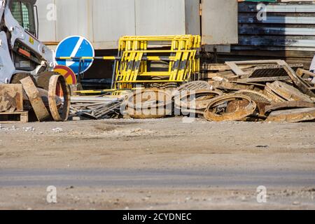 Ein Großteil der alten Schachtschächte, die gut verkauft wurden, stapelten sich in einem Haufen, neben vorübergehenden Straßenschildern und Notbarrieren Stockfoto