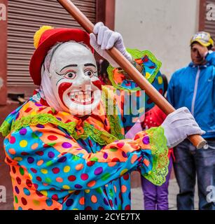 Latacunga, Ecuador - 22. September 2018 - ein Clown führt jede Nachbarschaft Gruppe in der Mama Negra Parade, seine Gruppe zu verkünden Stockfoto