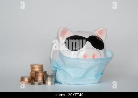 Der Zusammenbruch der Finanzmärkte und die Gefahr für finanzielle Ersparnisse aufgrund eines Pandemie-Virus.Masked Sparschwein Stockfoto