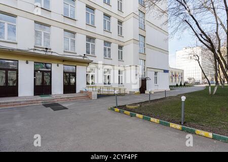 Schulgebäude mit leerem Innenhof. Klassisches lichtverputztes Schulhaus in Moskau, ein typisches Gebäude für Bildungseinrichtungen in den 30-50er Jahren Stockfoto