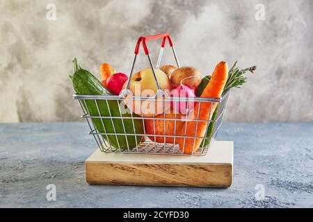 Verschiedene Gemüse und Früchte liegen in einem Supermarkt Korb auf einem Holzpodest. Platz für Text kopieren. Stockfoto