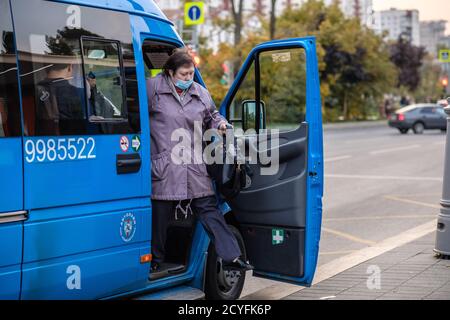 Moskau. Russland. September 25, 2020. Eine Erwachsene Frau in einer medizinischen Schutzmaske kommt aus der offenen Tür eines Minibusses. Die zweite Welle der Stockfoto