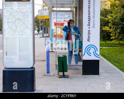 Moskau. Russland. September 25, 2020. Eine Erwachsene Frau steht in einem Pavillon der öffentlichen Verkehrsmittel, während sie auf einen Bus wartet. Eine Frau hält eine medizinische Maske in sich Stockfoto