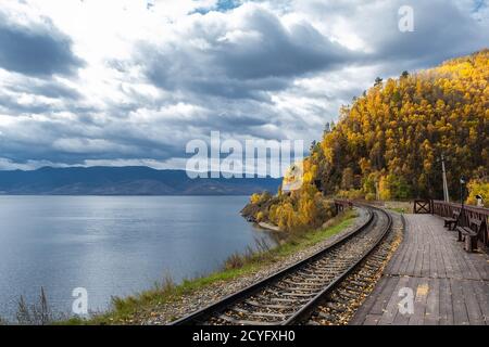 Küste des Baikalsees auf der Circum-Baikalbahn im Herbst. Malerische Herbstlandschaft mit bunten lebendigen Wald und dramatischen stürmischen Himmel. Stockfoto