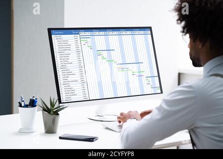 Nahaufnahme eines Geschäftsmanns, der auf Gantt Chart über Computer im Büro Stockfoto