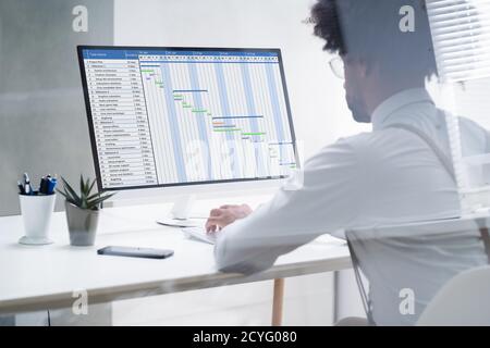 Nahaufnahme eines Geschäftsmanns, der auf Gantt Chart über Computer im Büro Stockfoto