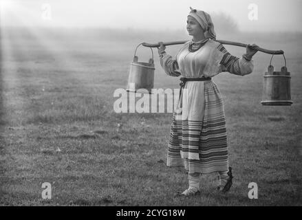 Besticktes Hemd und Eimer auf den Schultern einer jungen attraktiven Frau. Schwarz und Weiß Stockfoto