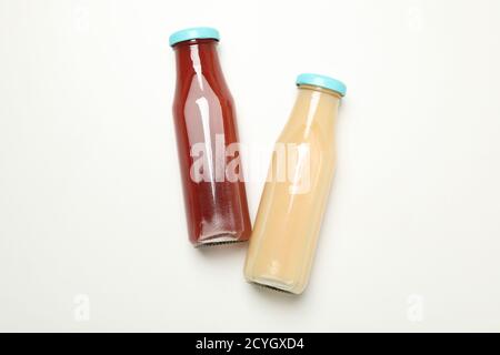 Flaschen mit Erdbeer- und Bananensaft auf weißem Hintergrund Stockfoto