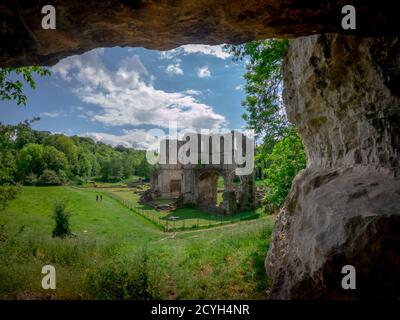 Roche Abbey, Rotherham, South Yorkshire, England, UK von Kalkstein Klippe Bergrücken Höhle hohen Winkel an einem hellen sonnigen Tag; zwei Menschen zu Fuß am Zaun Stockfoto