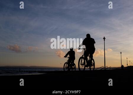 Zwei Radfahrer fahren am Abend im August am Strand des Fisherman’s Walk in Bournemouth kurz nach der Abenddämmerung auf dem Prom entlang. 05. August 2016. Pho Stockfoto