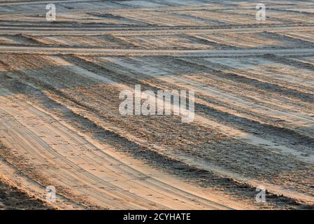 Sand am Strand, der bei Sonnenaufgang mit einem Traktor eingeebnet wurde. Stockfoto