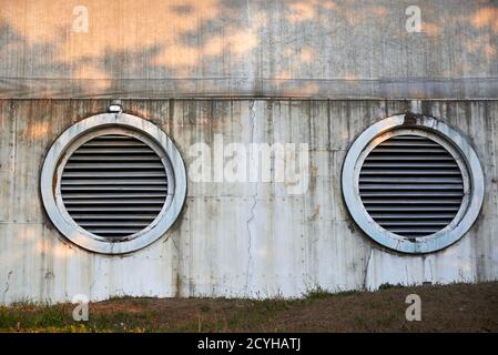 Große Lüftungskreise an einer alten zerstörten Wand. Stockfoto