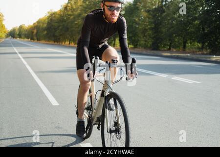 Nahaufnahme eines Radfahrers auf einem Schotterrad. Fahrradtraining im Freien, modern aussehendes Fahrrad und Sportler, aktiver Lebensstil Stockfoto