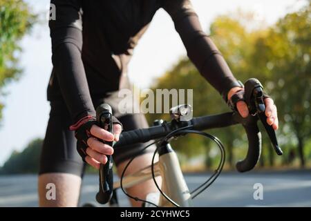 Hände eines Radfahrers, der auf einem Rennradlenker ruht. Radfahren, Fahrradsport Training im Freien Stockfoto