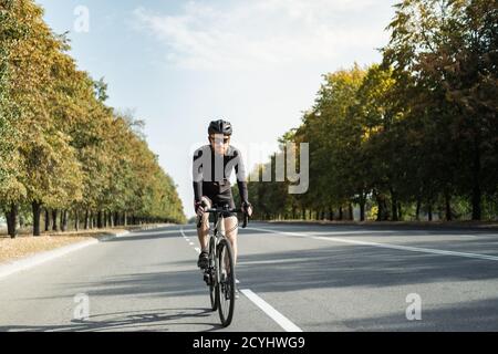 Mann auf einem Schotterrad auf der Straße. Gut ausgerüsteter Radfahrer, der ein modernes Fahrrad im Freien fährt Stockfoto