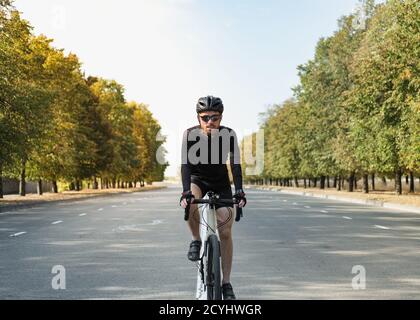 Porträt eines Mannes auf einem Schotterrad auf der Straße. Gut ausgerüsteter Radfahrer, der ein modernes Fahrrad im Freien fährt Stockfoto