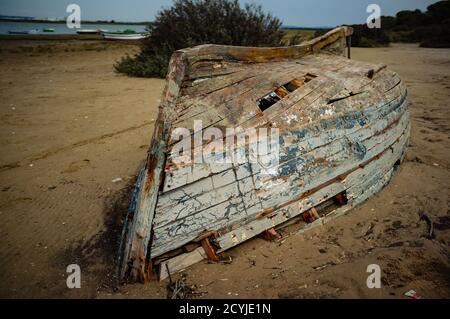 Alte verlassene beschädigte Fischerboot umgedreht am Strand Stockfoto