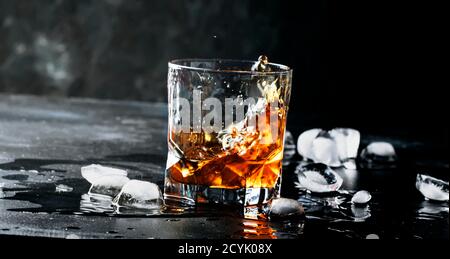 Whiskey mit Eis, Spritzer aus Glas, dunkler Hintergrund, selektiver Fokus Stockfoto