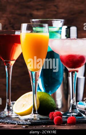 Farbenfrohe Sommercocktails. Kalte alkoholische Getränke und Getränke: mimosa, Cosmopolitan, Himbeere margarita und blau hawaii auf Holztisch Hintergrund w Stockfoto