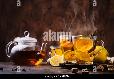 Winter oder Herbst heißen Heiltee mit Ingwer, Honig, Zitrone und Gewürzen in Glas Tasse mit Dampf, rustikalen Holzhintergrund Stockfoto