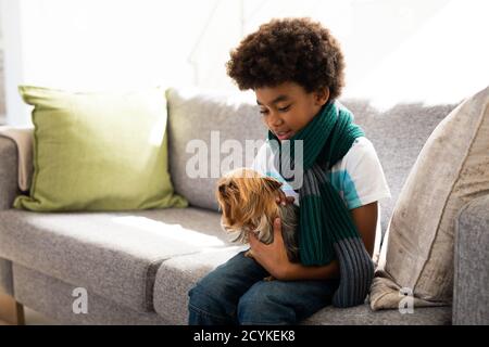 Kleiner Junge, der seinen Hund zu Hause hält Stockfoto