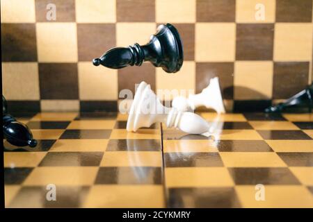 Konzept, Schachfiguren fallen auf das Schachbrett Stockfoto