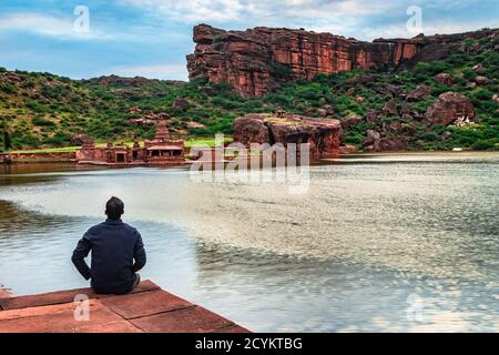 Mann, der am Seeufer sitzt und die Natur beobachtet Dawn Bild zeigt die Schönheit der Bhutanatha Tempel auf Die Ufer von Agastya Tirtha bei Badami k Stockfoto