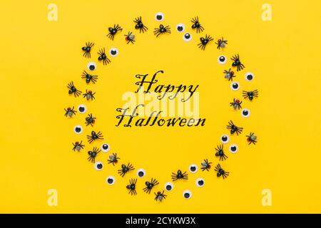 Runder Rahmen aus schwarzen Spinnen und Fliegen, Stachelaugen auf gelbem Hintergrund Draufsicht Flat Lay Happy Halloween Kreativkonzept Weihnachtskarte Mock Up Stockfoto