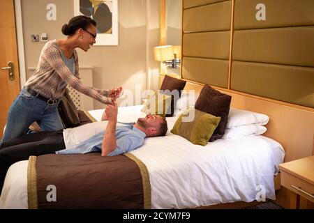 Ein multiethnisches Paar, das in einem Hotelzimmer verspielt ist, hat einen romantischen Abend geplant. Stockfoto