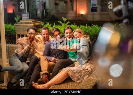 Eine Gruppe verschiedener Freunde, die ein Selfie auf einem Smartphone im Freien in einer Bar/Restaurant machen, feiern und Spaß haben zusammen, sie machen Stockfoto